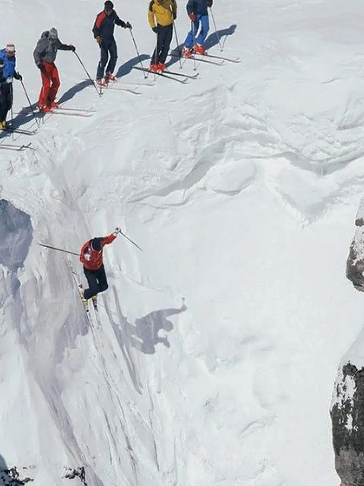 Skieurs sautant au-dessus d'une corniche enneigée.