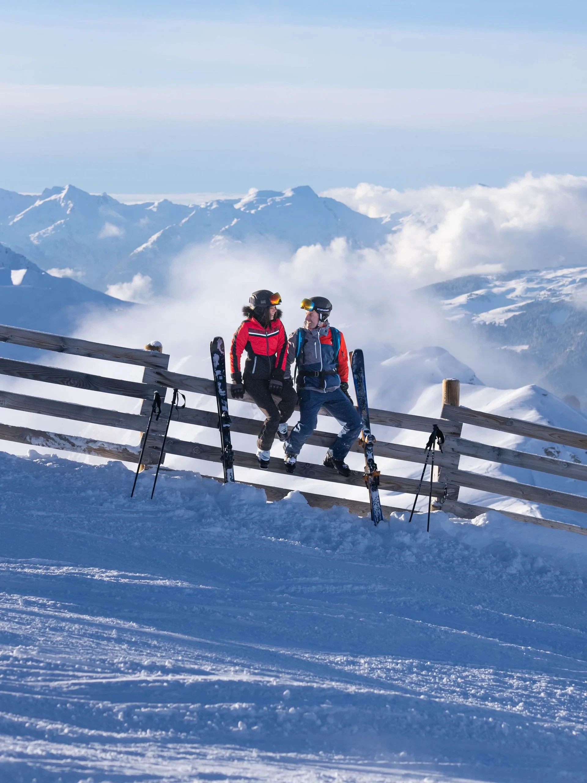Deux skieurs assis sur une clôture enneigée.