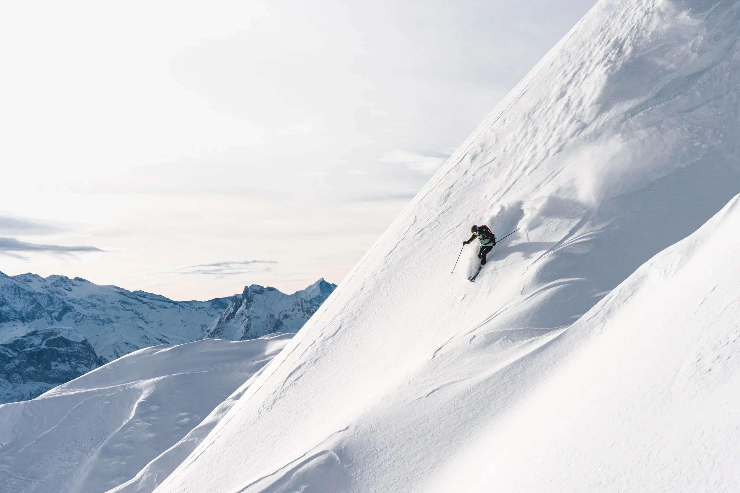 Skieur dévalant une pente enneigée en montagne.