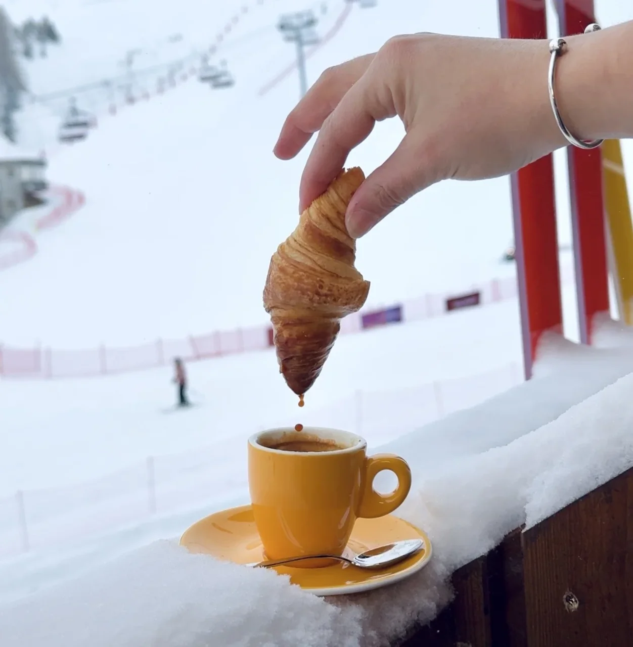 Croissant trempé dans café en montagne enneigée.