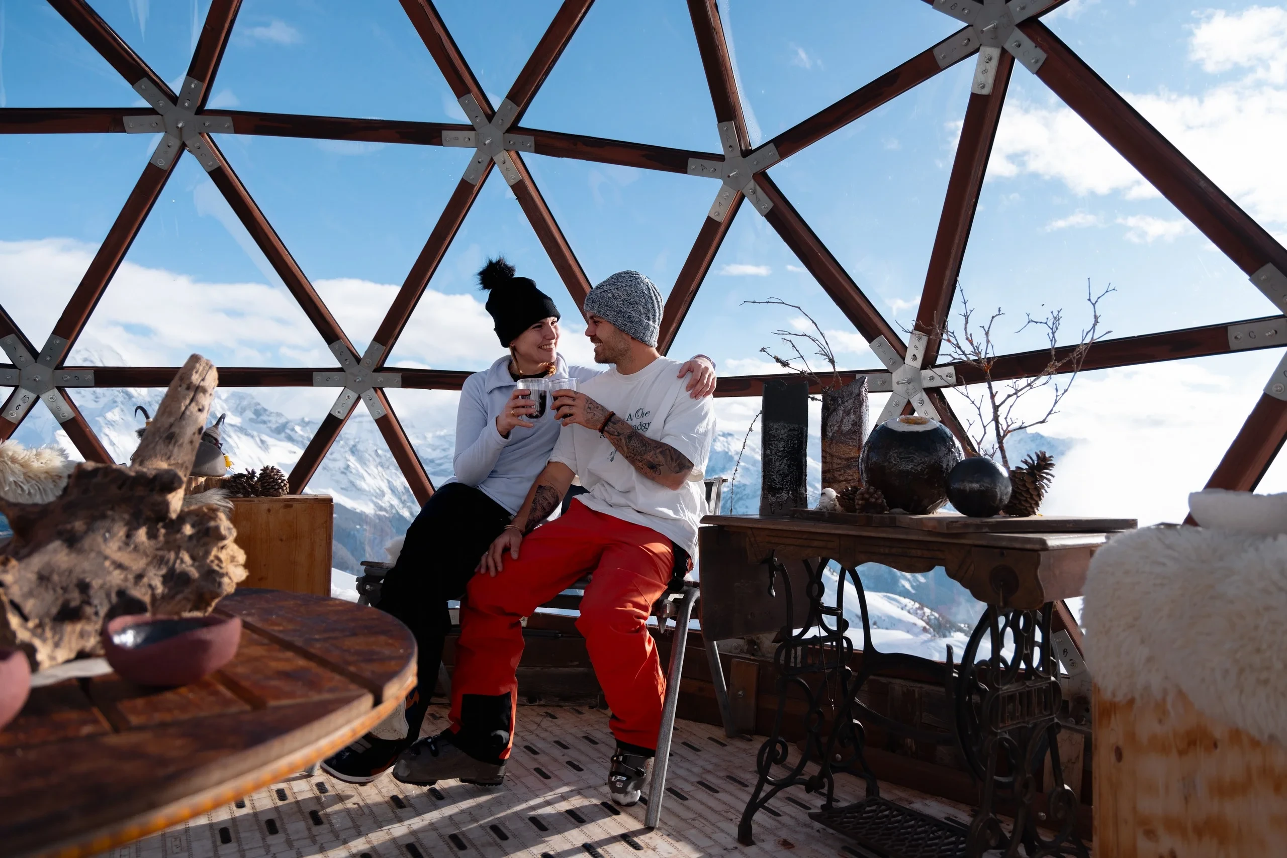 Couple souriant dans un dôme géodésique en montagne.