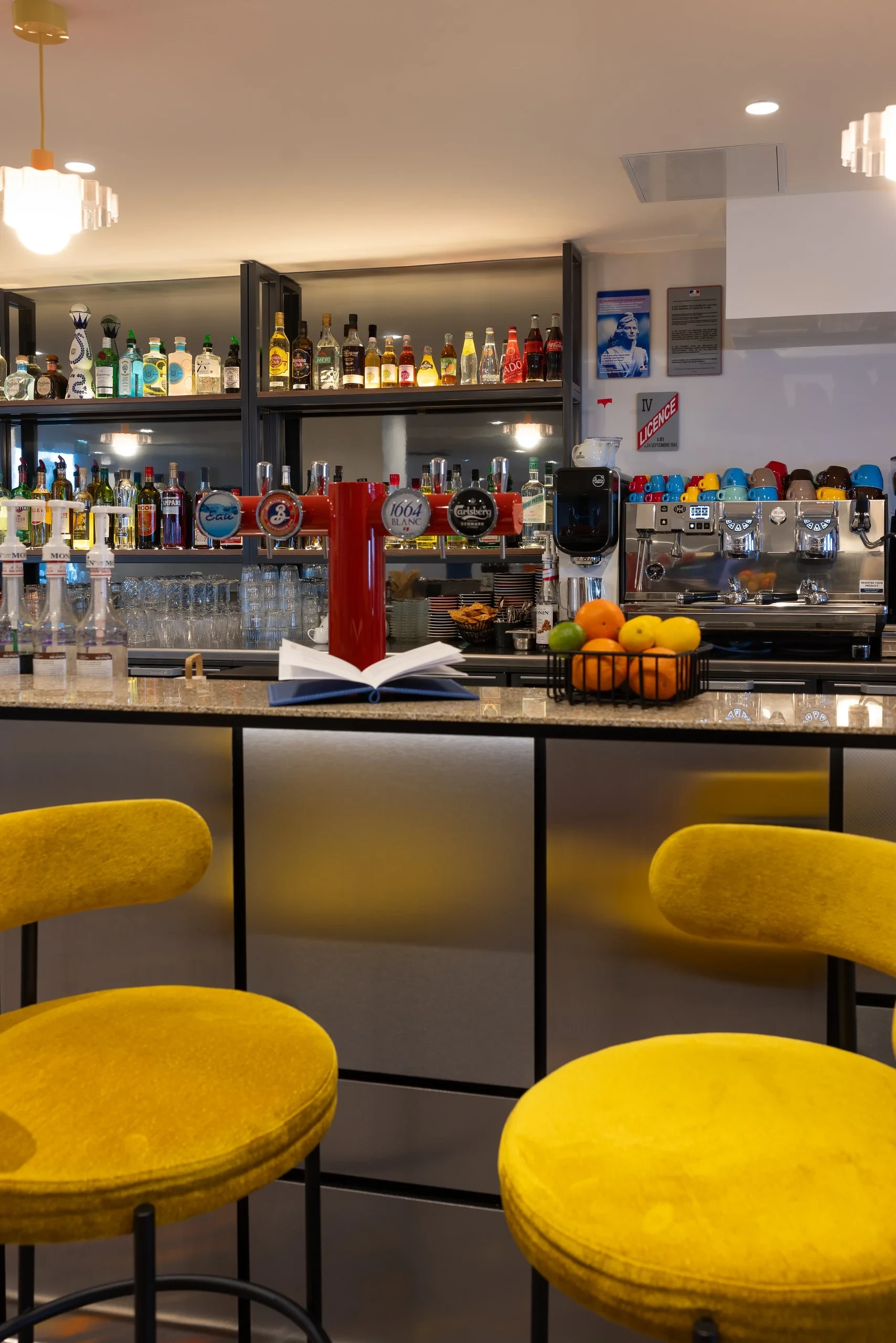 Bar avec bouteilles et tabourets jaunes.