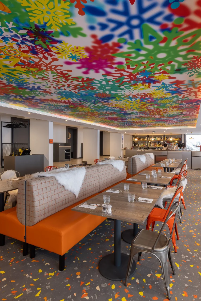 Restaurant avec plafond coloré et tables modernes.