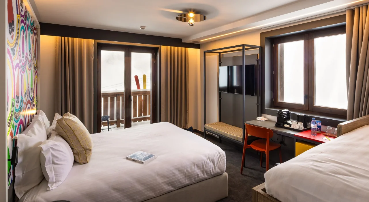 Chambre d'hôtel moderne avec balcon enneigé.