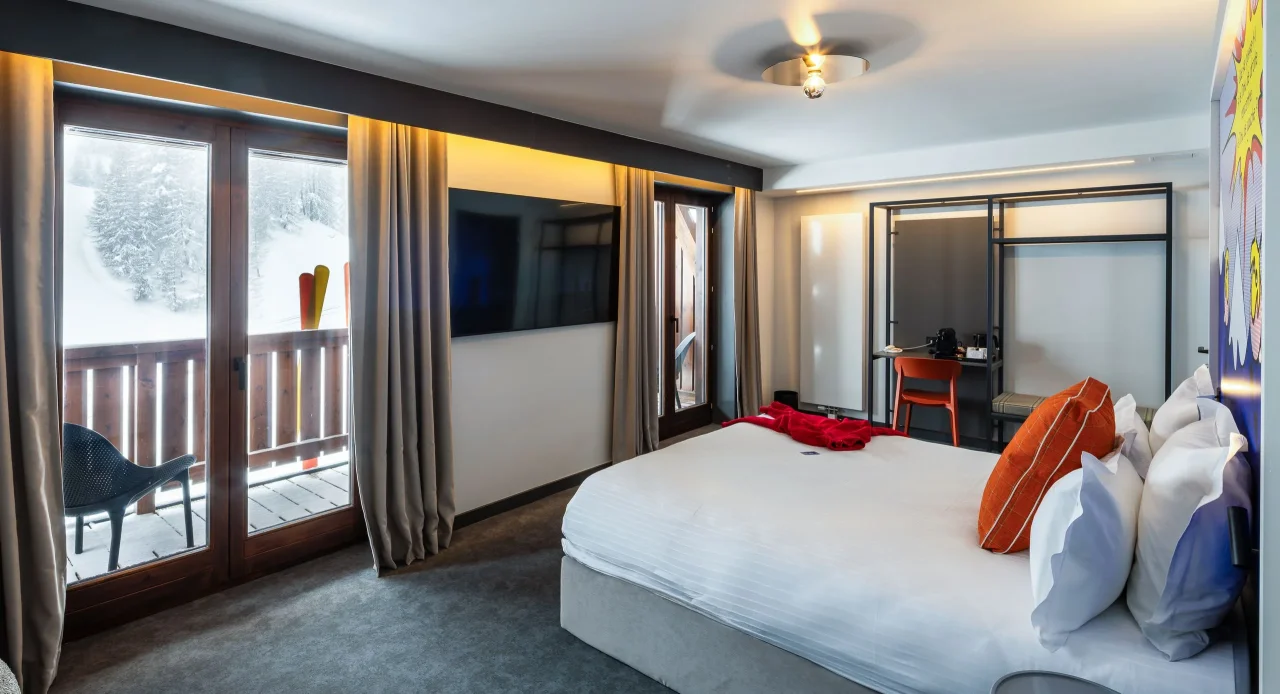 Chambre d'hôtel moderne avec balcon enneigé.