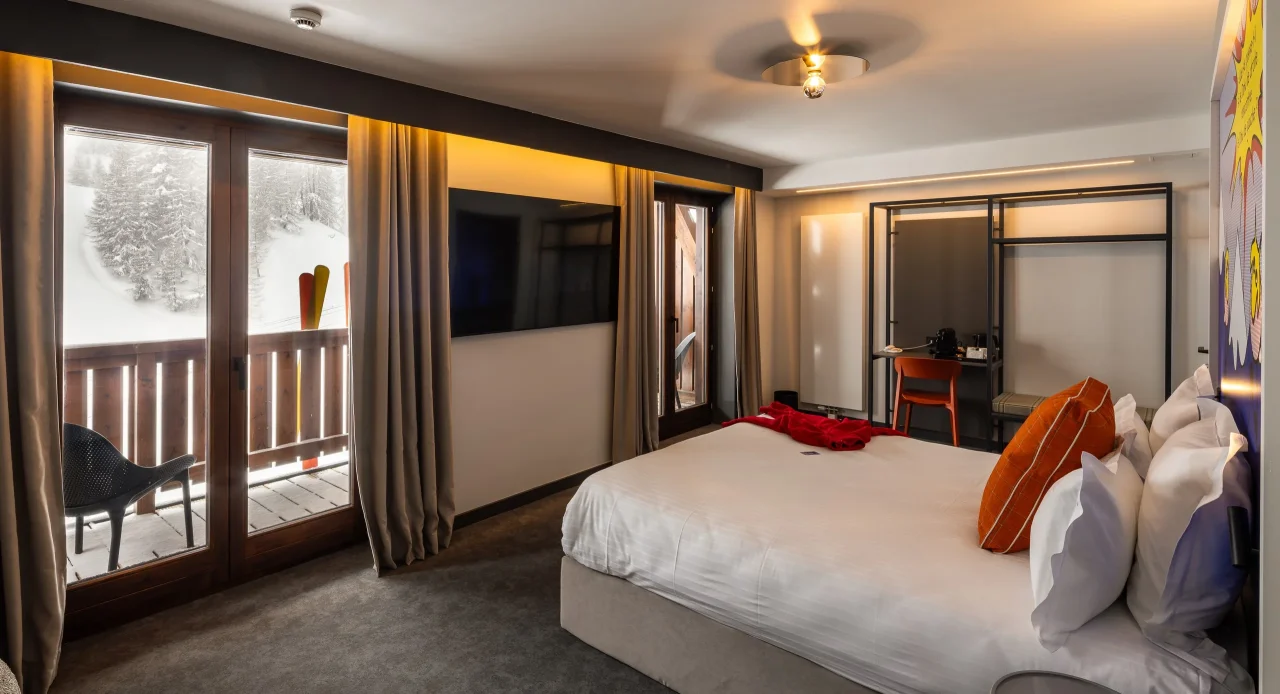Chambre d'hôtel avec vue sur montagne enneigée.
