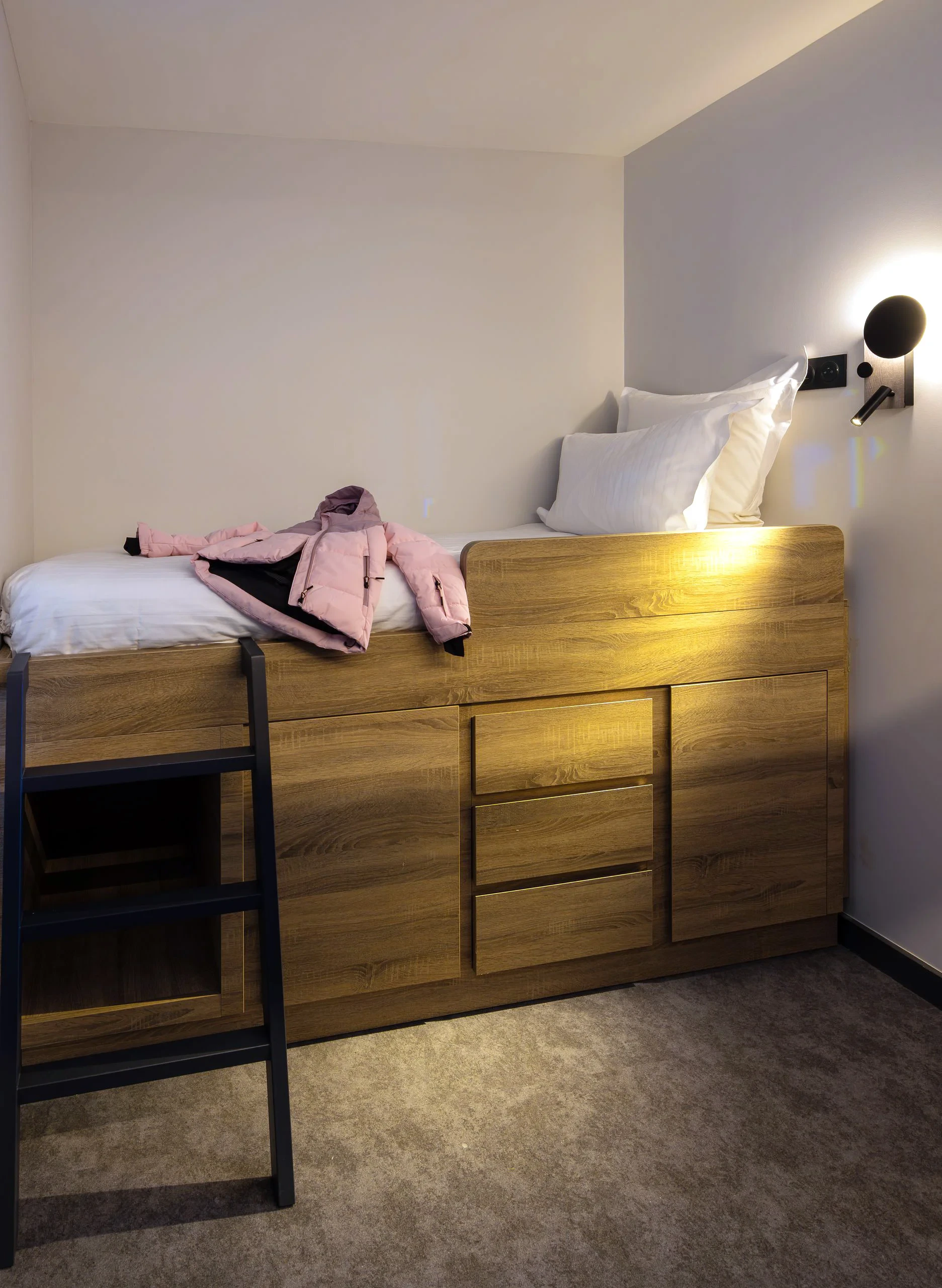 Lit en bois avec échelle et veste rose.