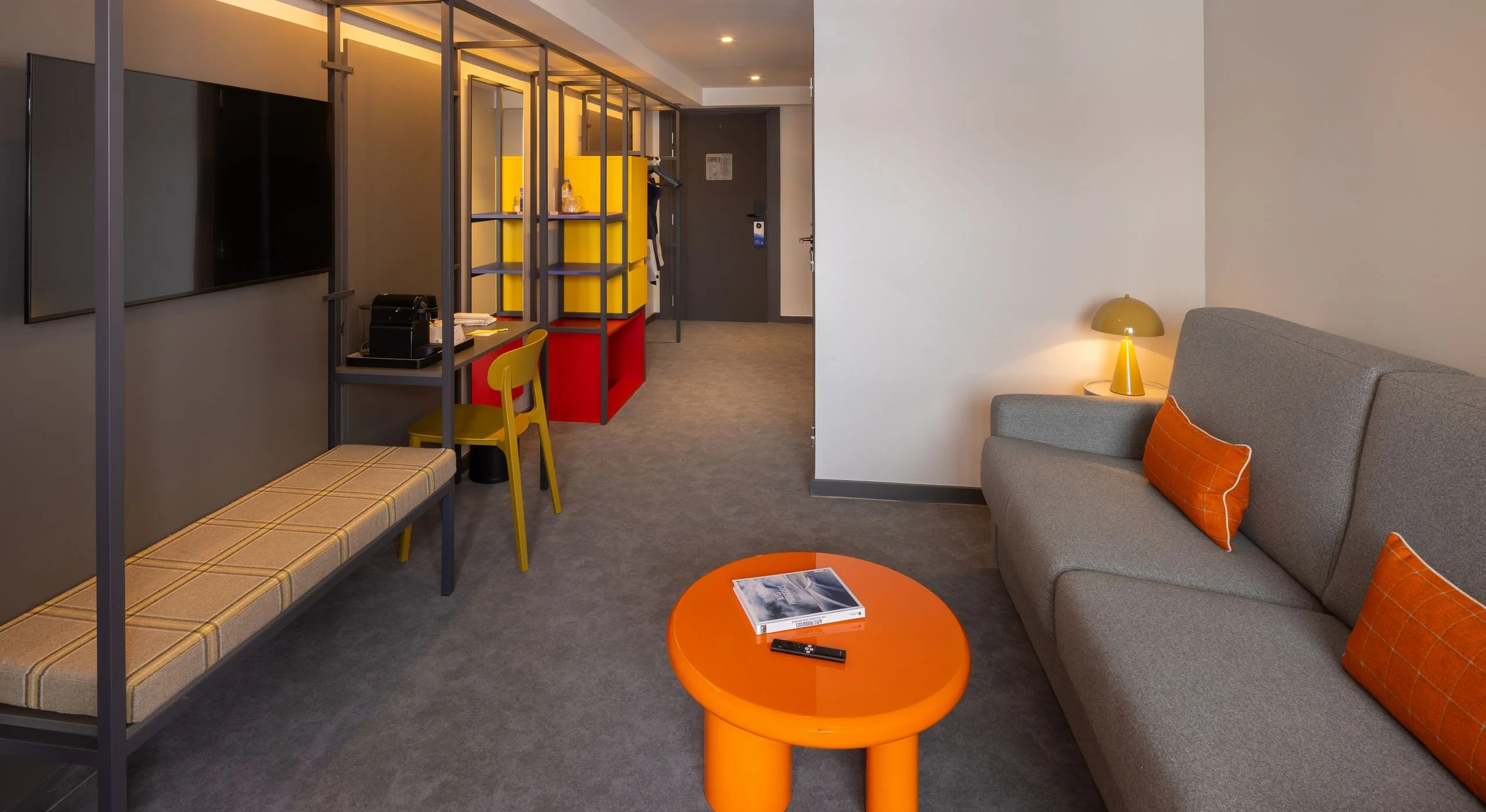 Salon moderne avec décoration colorée et canapé gris.