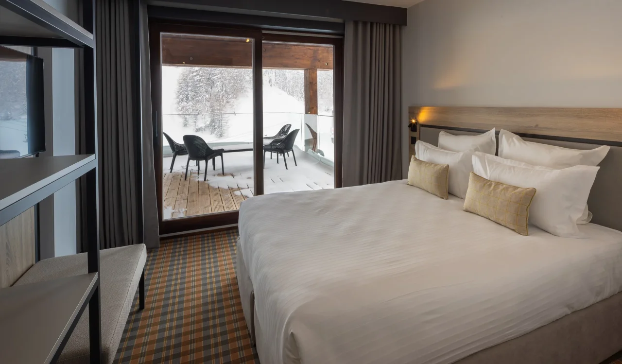 Chambre d'hôtel avec vue sur balcon enneigé.