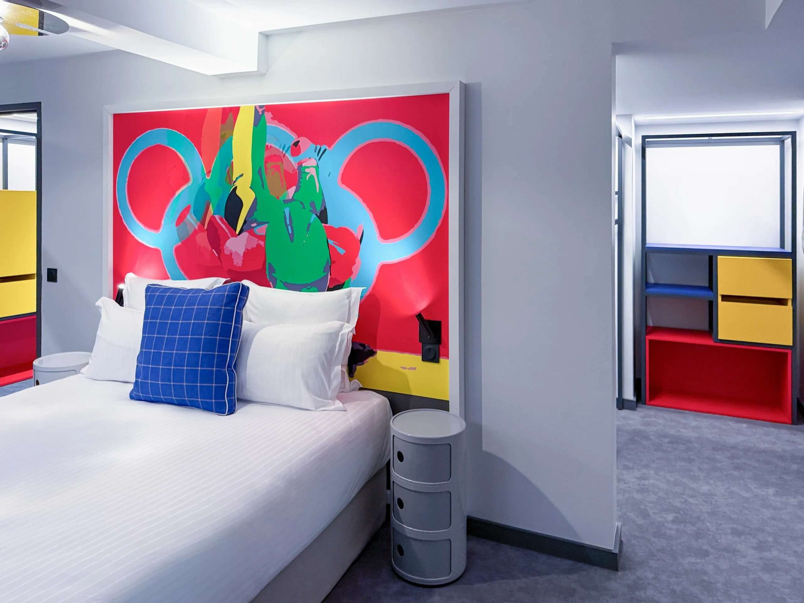 Chambre d'hôtel moderne avec oeuvre murale colorée.