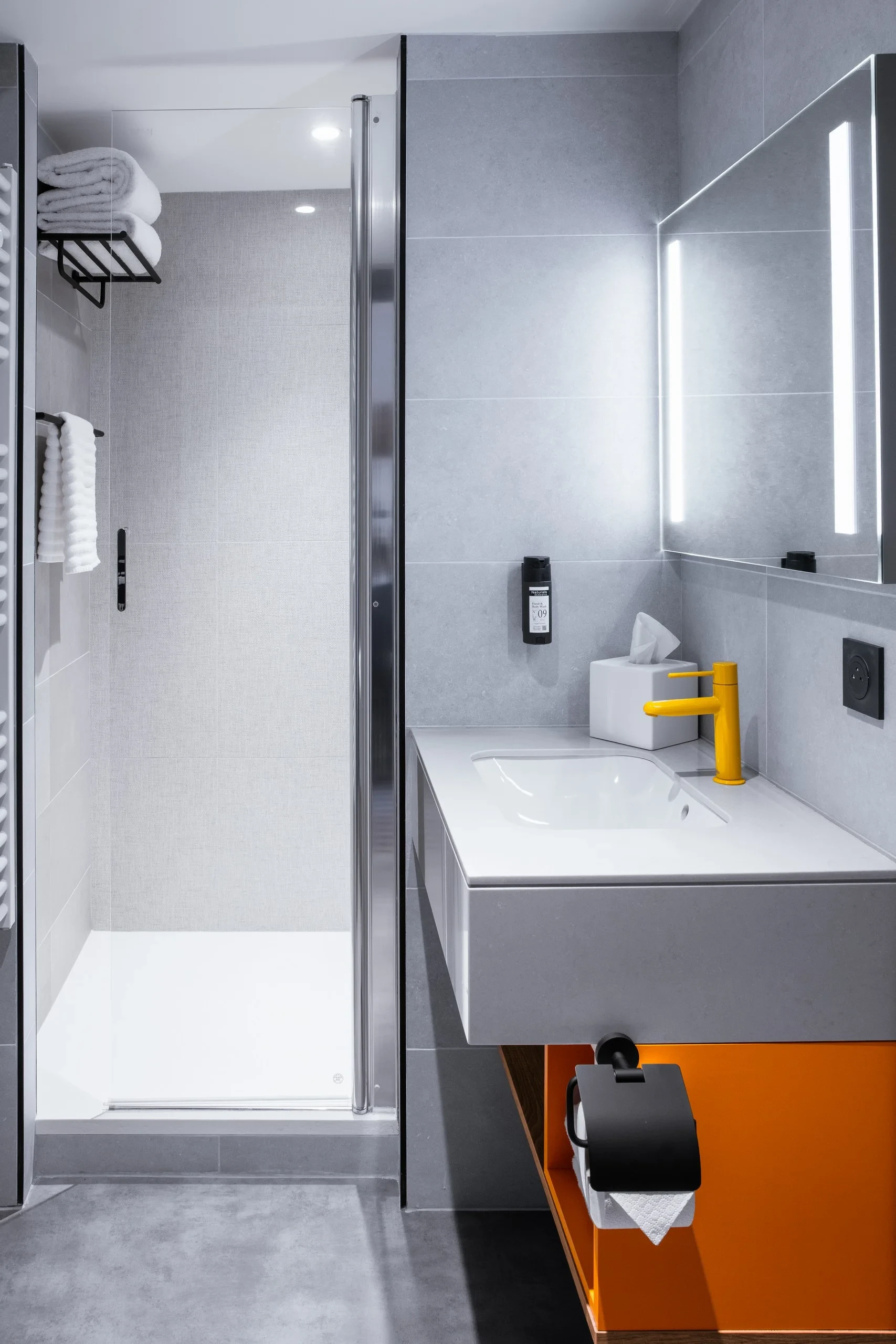 Salle de bain moderne avec douche et lavabo.