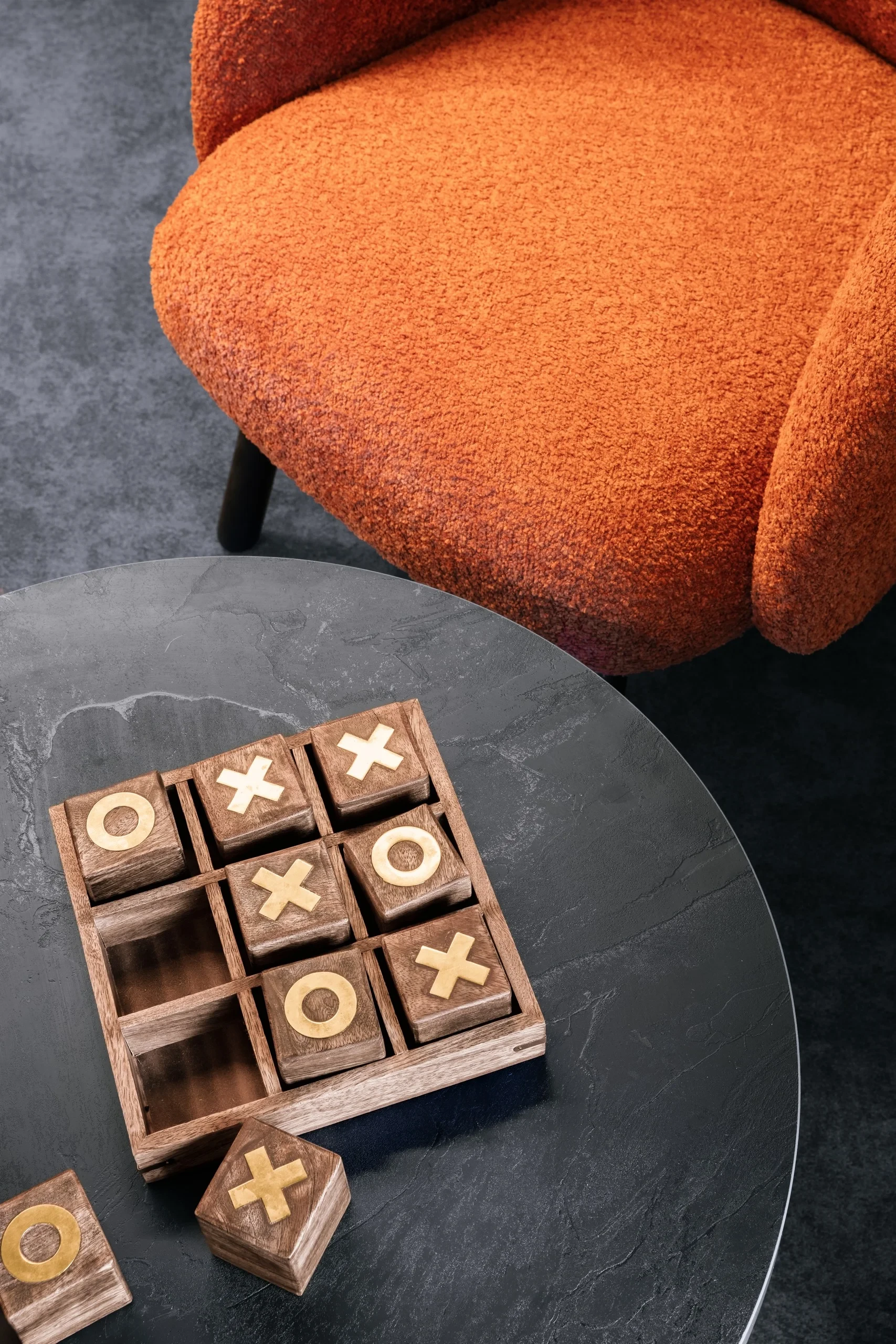 Fauteuil orange et jeu de morpion en bois.