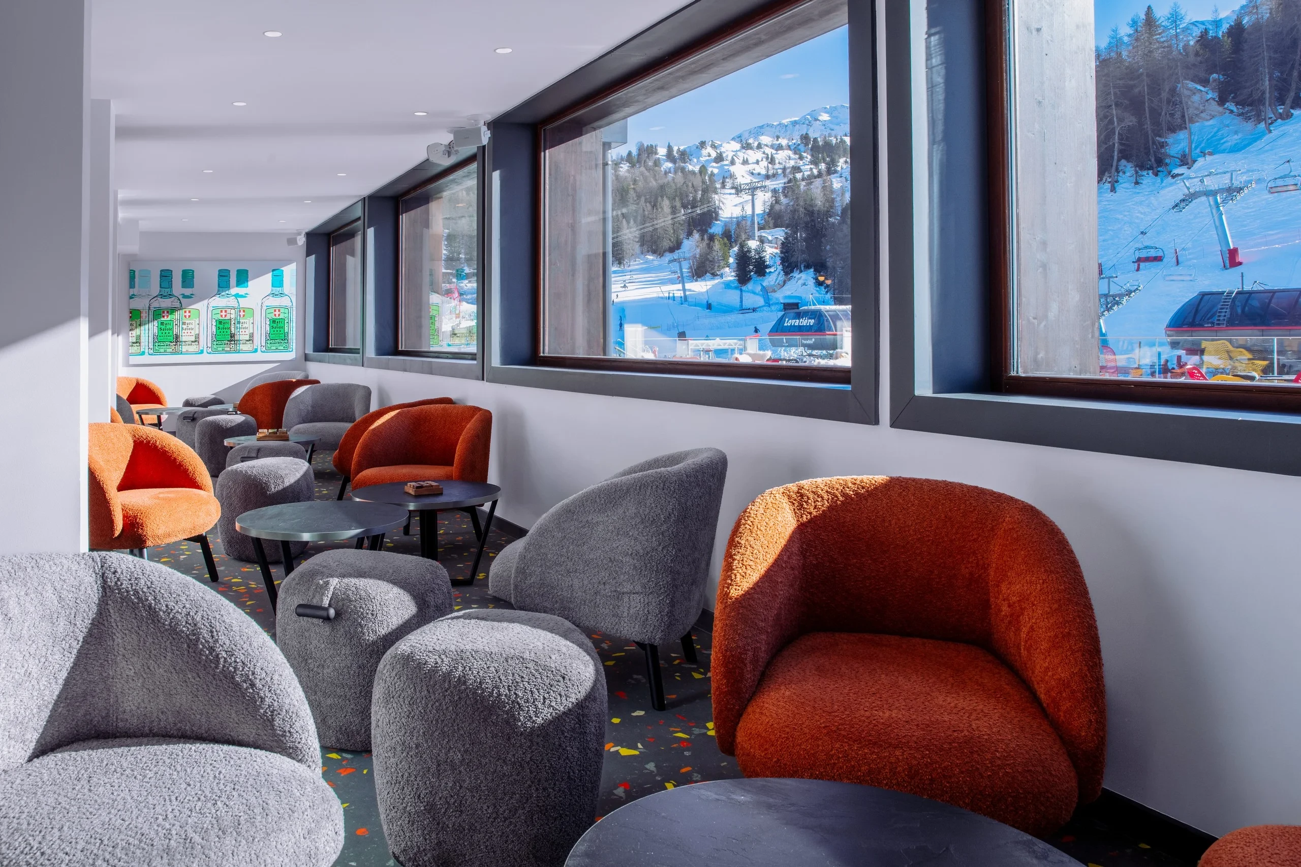 Salle avec fauteuils modernes et vue sur montagne enneigée.