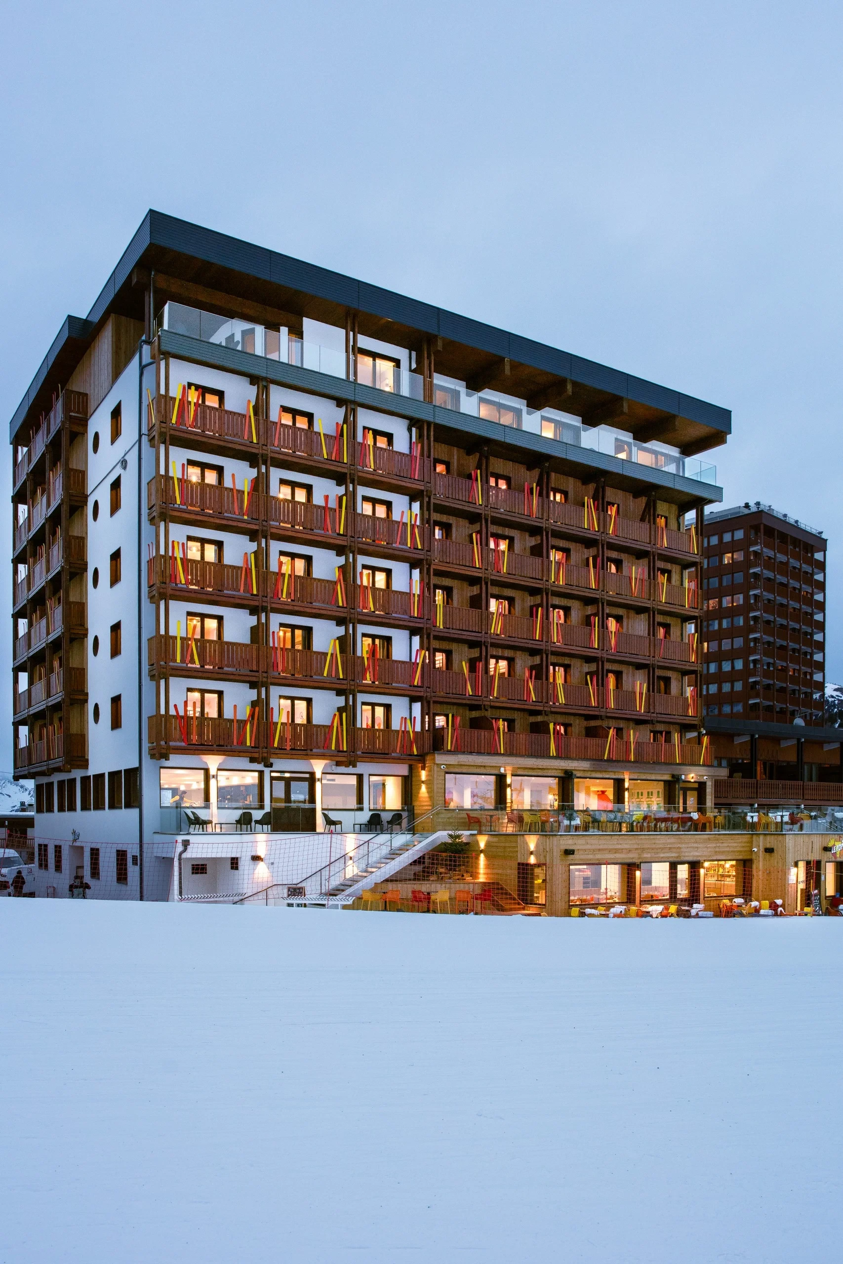Bâtiment moderne avec balcons éclairés au crépuscule.