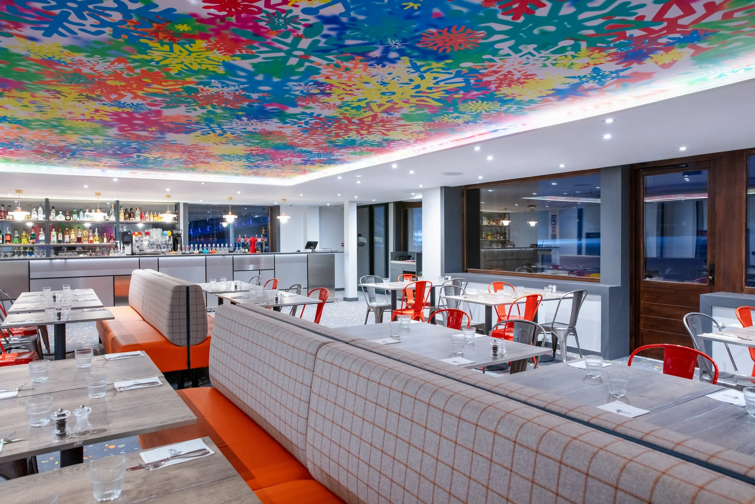 Restaurant moderne avec plafond coloré et mobilier contemporain.