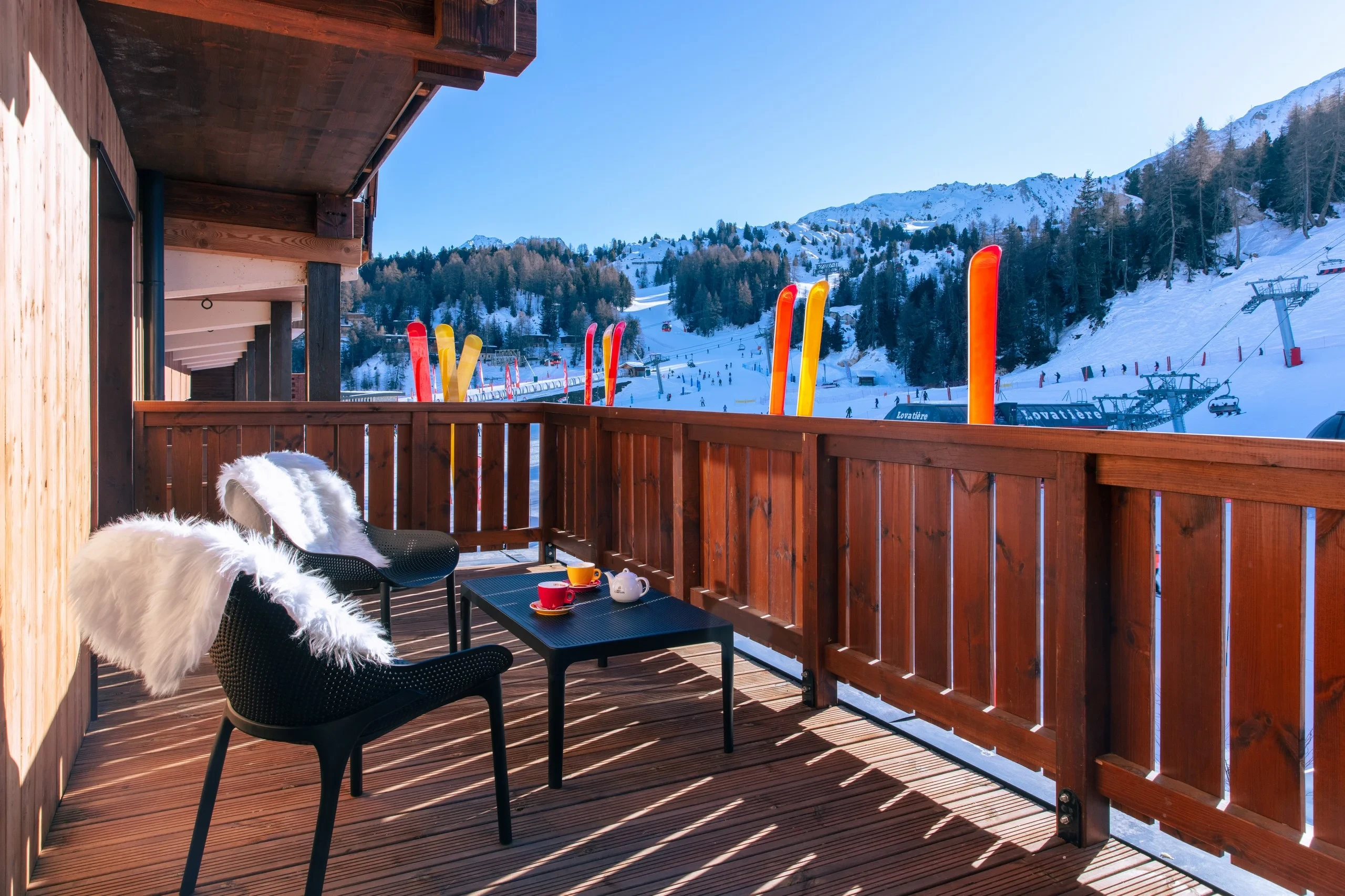 Terrasse en bois avec vue sur pistes neigeuses.