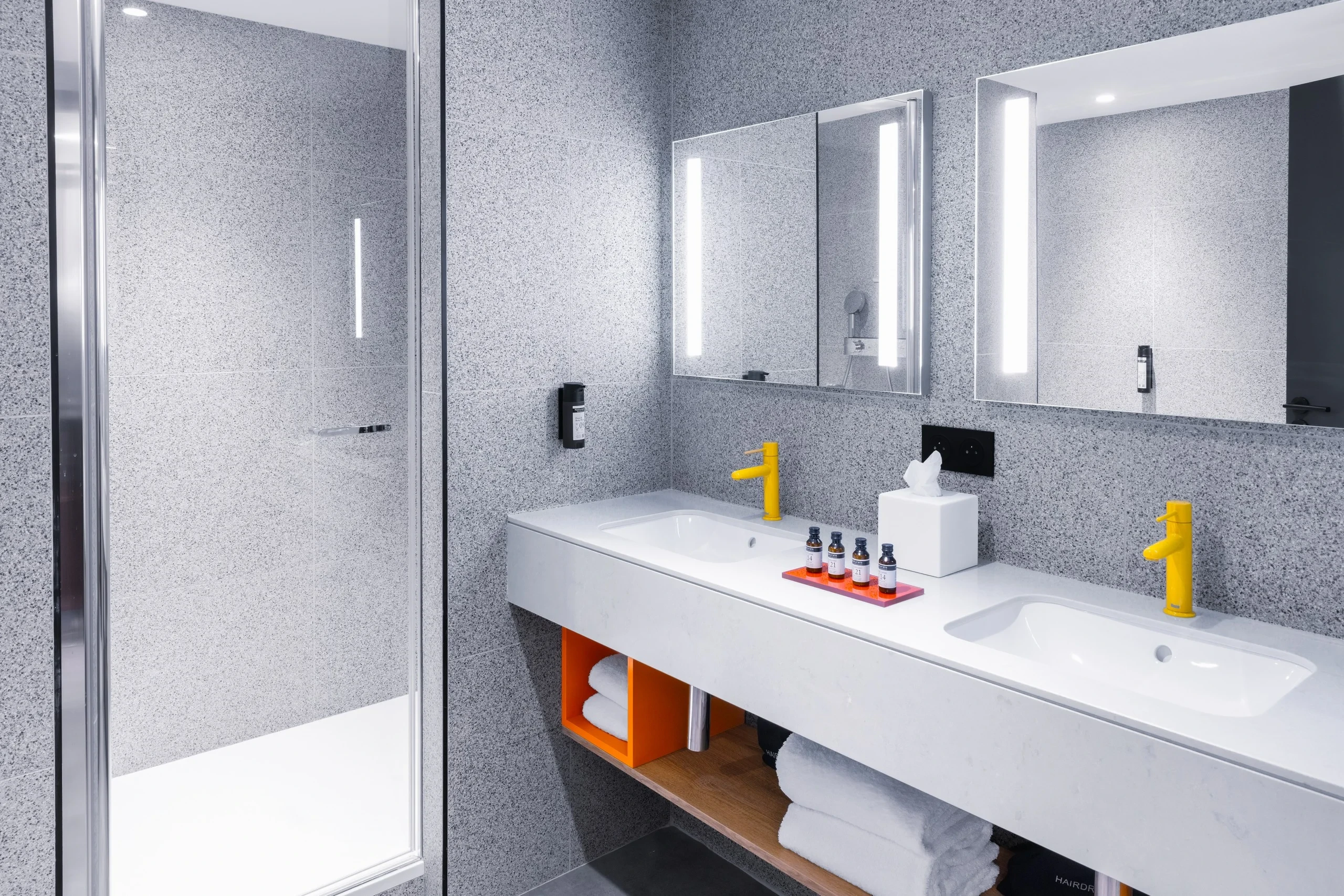 Salle de bain moderne avec douche et double lavabo.