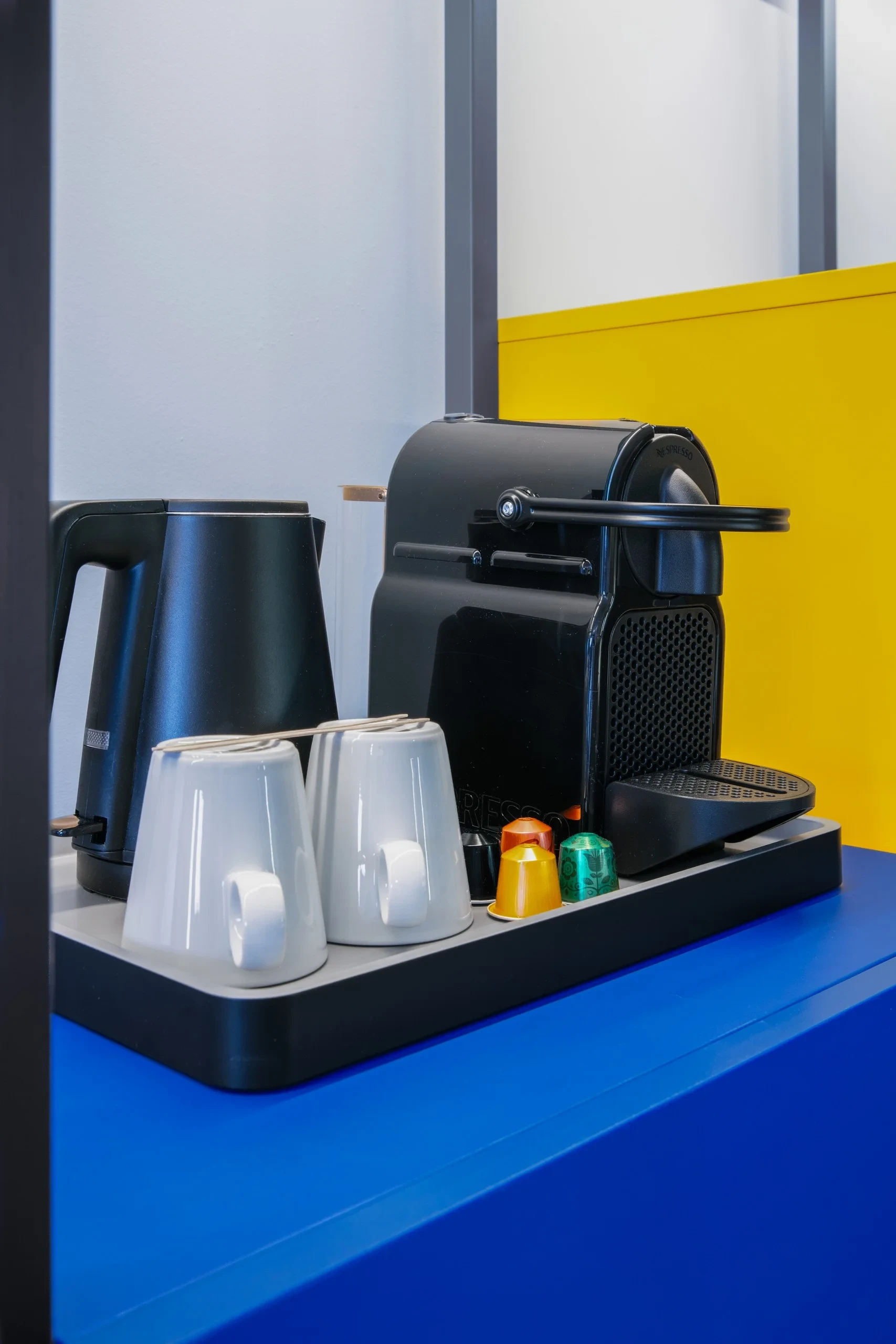 Machine à café avec tasses et capsules colorées.