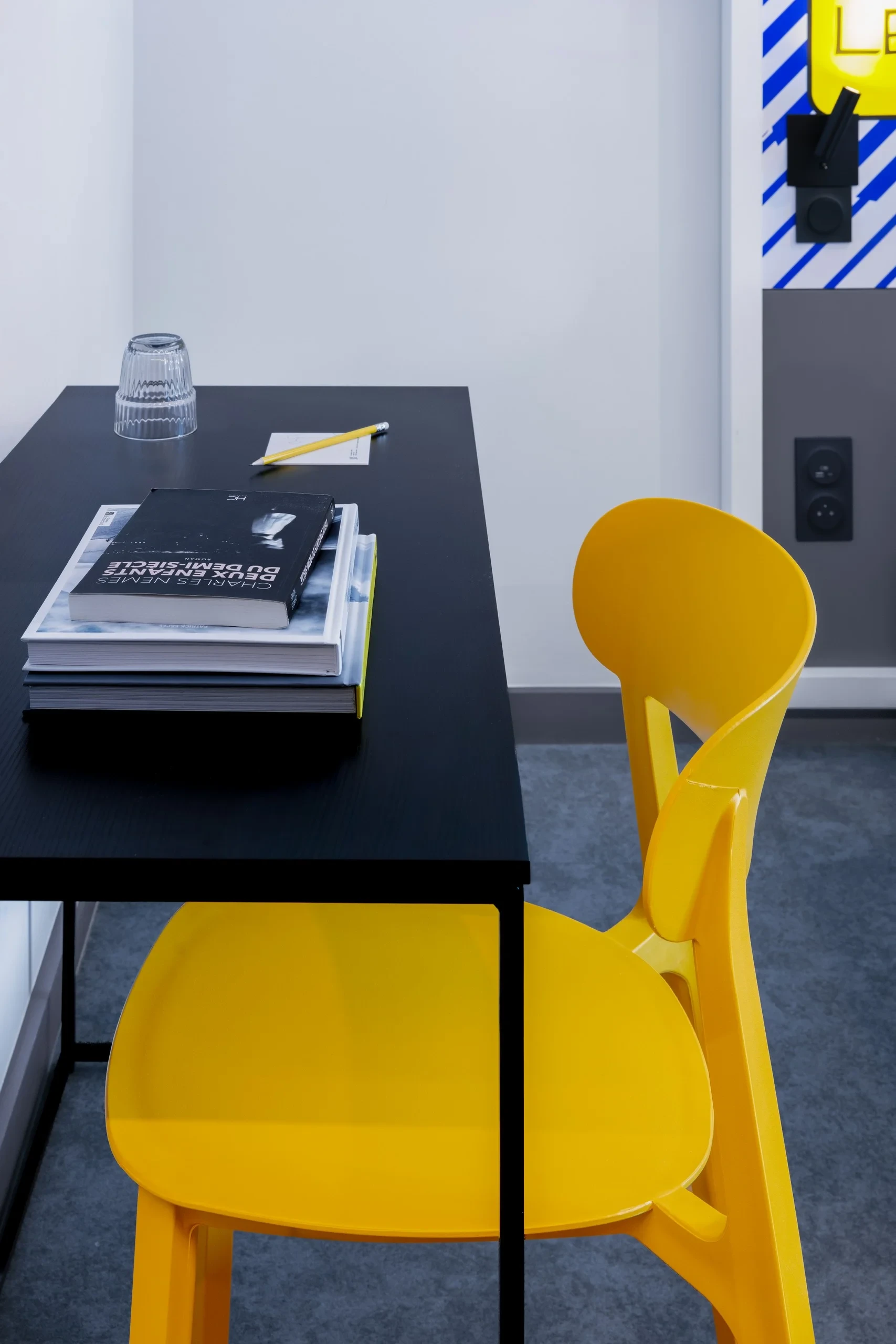 Table noire avec chaise jaune et livres