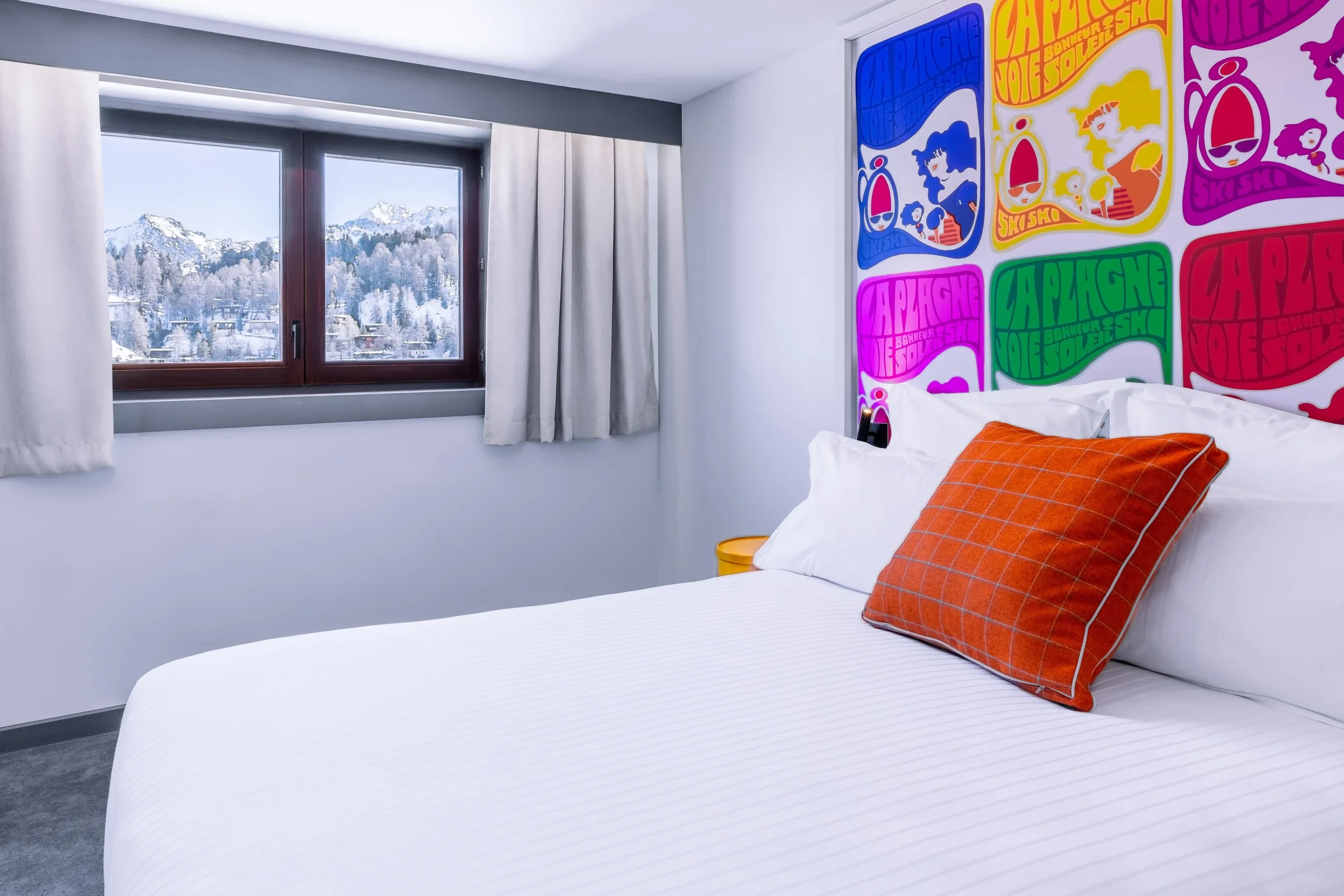 Chambre avec vue sur montagnes enneigées et décor coloré.