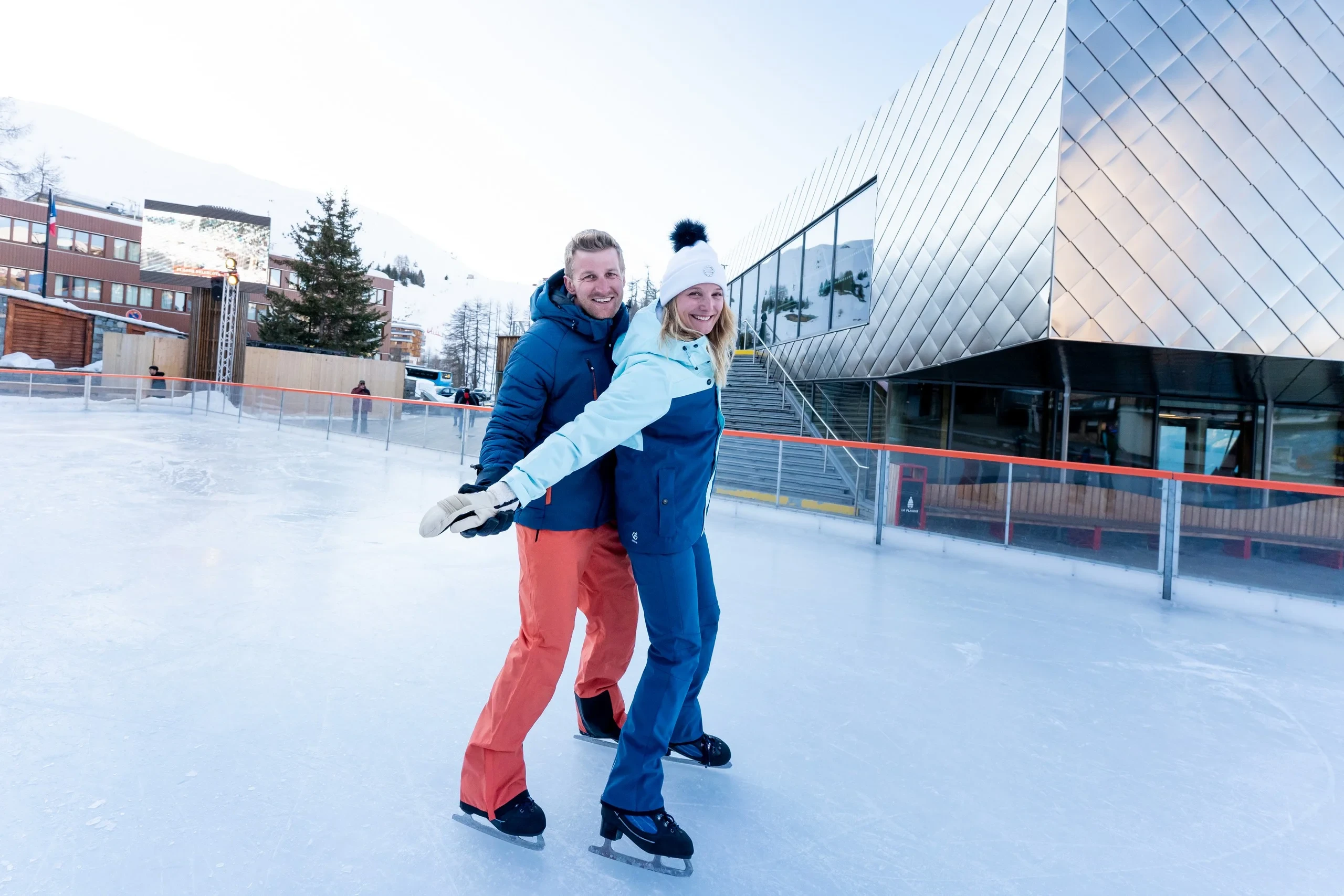 Deux personnes patinent ensemble sur la glace extérieure.